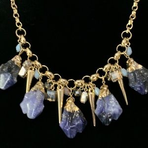 Gold tone chain with purple, blue, white & black tone crystal like necklace.
